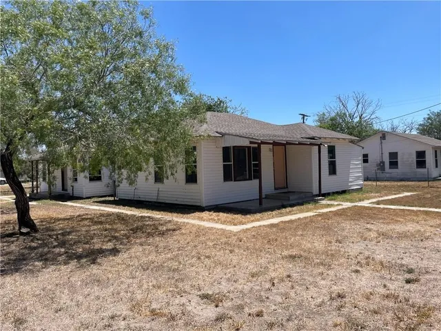 a view of a house with a yard and large tree