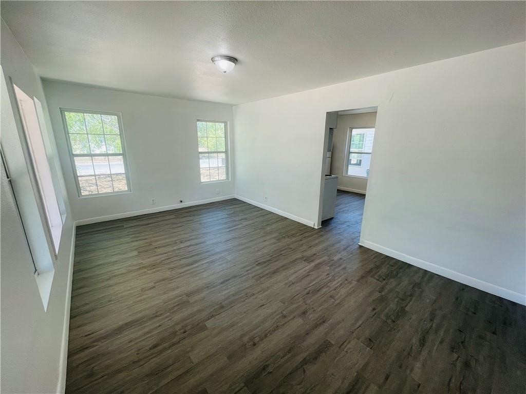 303 East Hackberry Street Mathis, TX 78368 - Photo 4 of 13 an empty room with wooden floor and windows