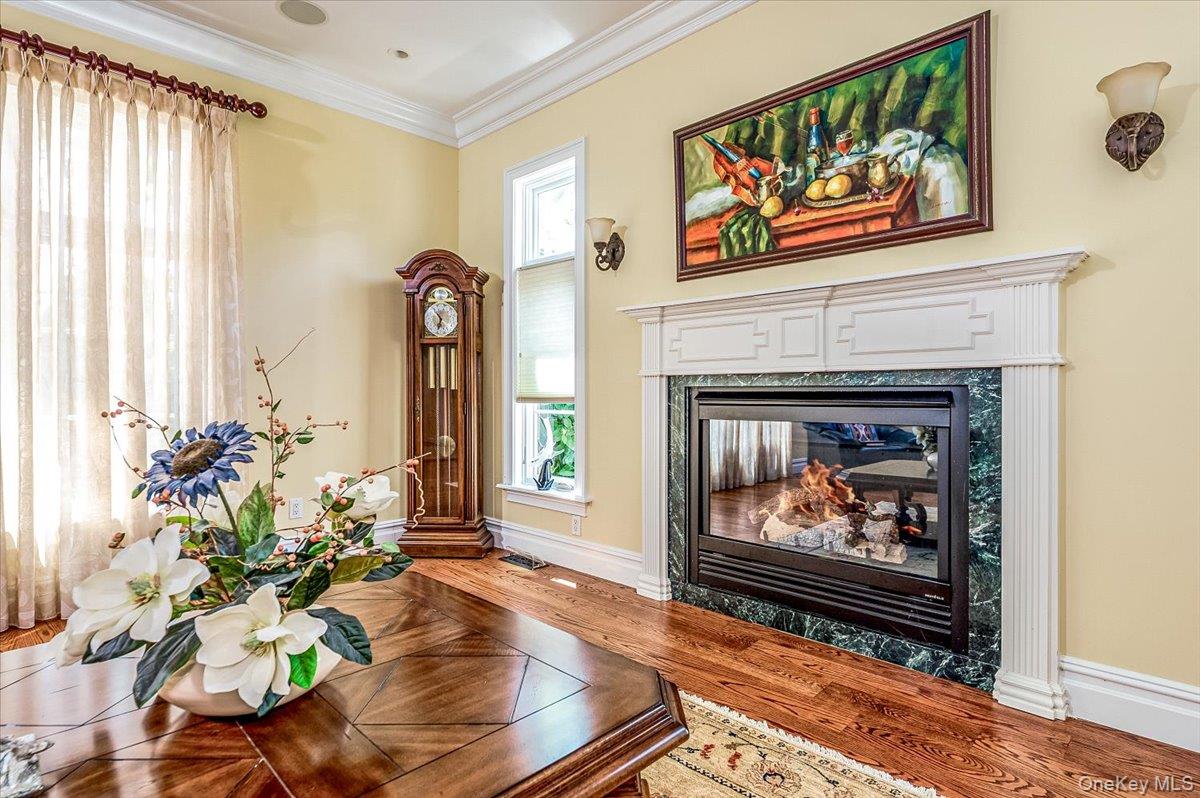 83 Ithaca Avenue Atlantic Beach, NY 11509 - Photo 14 of 45 Living area featuring wood finished floors, a fireplace, healthy amount of natural light, and crown molding