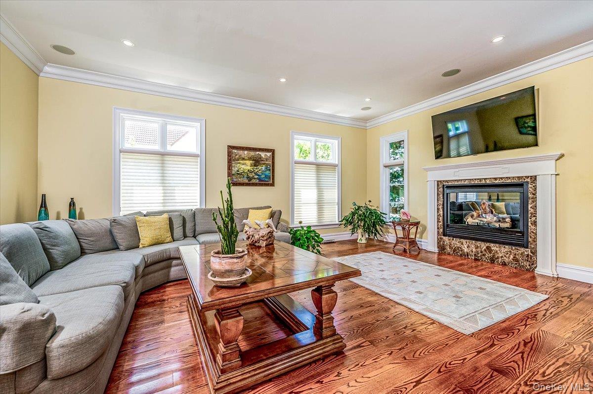 83 Ithaca Avenue Atlantic Beach, NY 11509 - Photo 16 of 45 Den featuring crown molding, wood finished floors, a glass covered fireplace, and recessed lighting