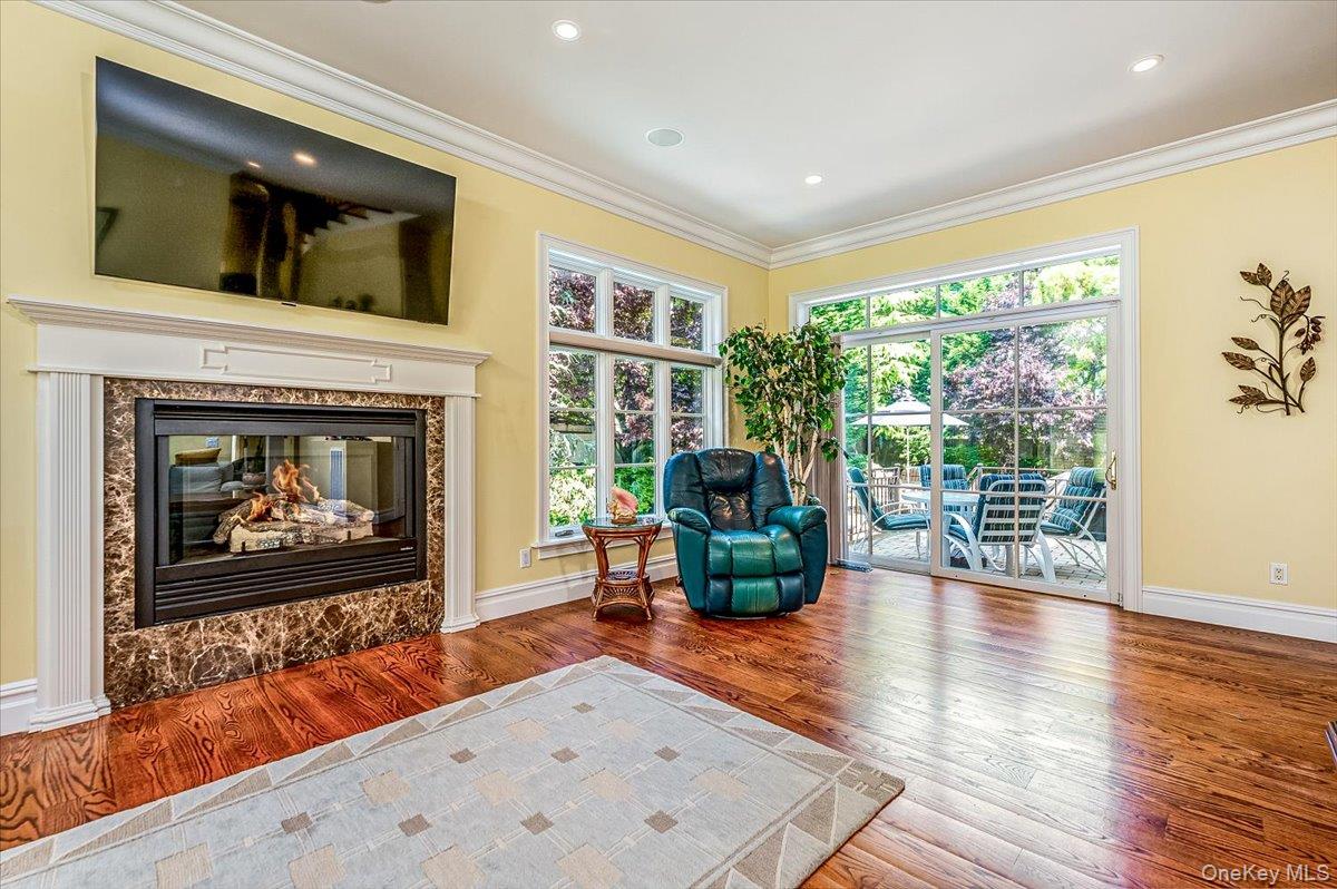 83 Ithaca Avenue Atlantic Beach, NY 11509 - Photo 17 of 45 Den featuring wood finished floors, crown molding, a premium fireplace, and recessed lighting