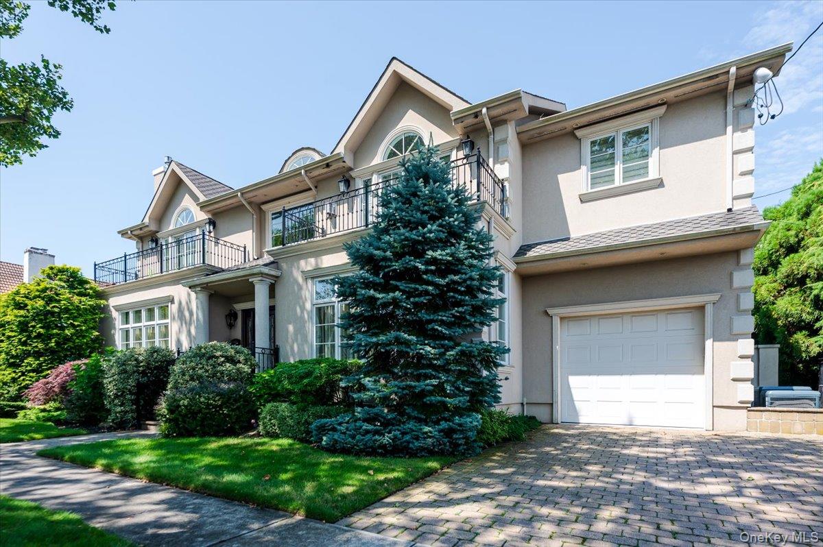 83 Ithaca Avenue Atlantic Beach, NY 11509 - Photo 2 of 45 View of front facade featuring stucco siding, an attached garage, decorative driveway, and a balcony