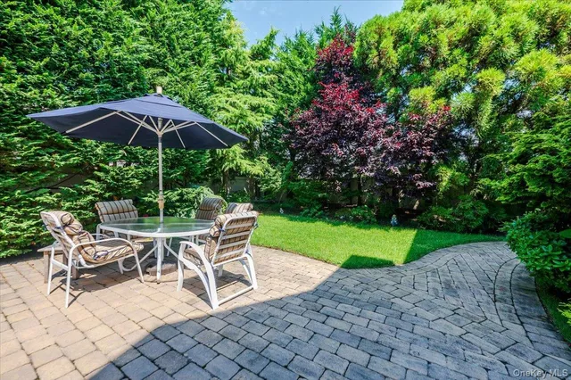 a view of a patio with table and chairs potted plants and floor to ceiling window