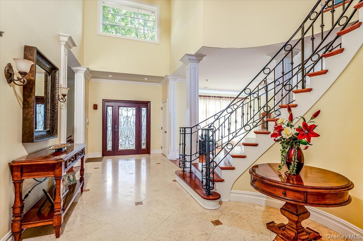 83 Ithaca Avenue Atlantic Beach, NY 11509 - Photo 5 of 45 Tiled foyer featuring ornate columns, plenty of natural light, a towering ceiling, crown molding, and stairs