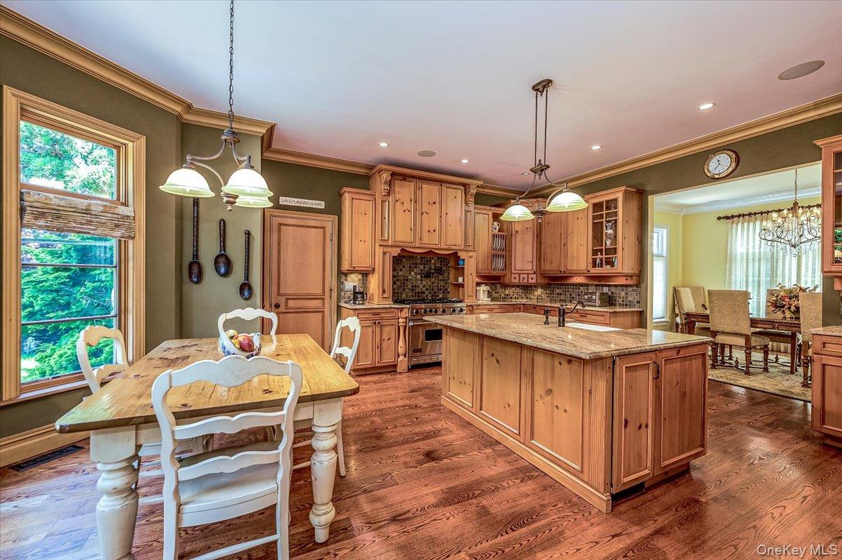 83 Ithaca Avenue Atlantic Beach, NY 11509 - Photo 7 of 45 Kitchen with high end range, a center island with sink, crown molding, light stone countertops, and glass insert cabinets