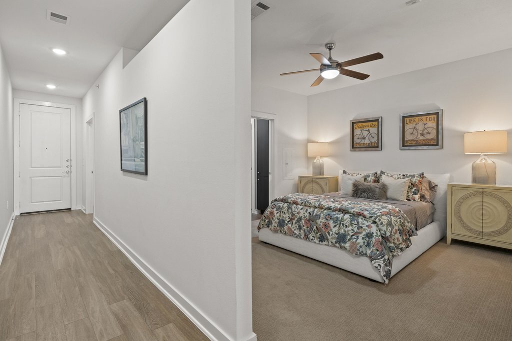 1900 Barton Springs Road, Unit 5009 Austin, TX 78704 - Photo 17 of 35 Step into a comfortable bedroom featuring a ceiling fan and soft carpeting, adjoining a hallway with durable wood-look flooring.