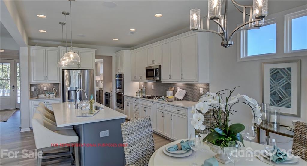 a kitchen with stainless steel appliances granite countertop a sink a stove and a dining table