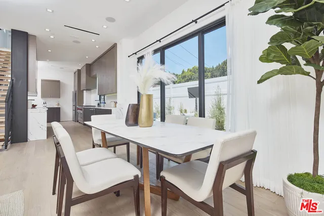 a large kitchen with stainless steel appliances a sink dishwasher and cabinets with wooden floor