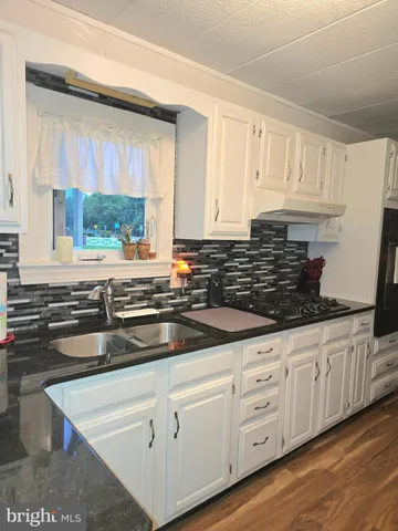 a kitchen with granite countertop white cabinets and white stainless steel appliances