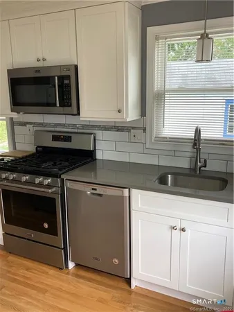 a kitchen with stainless steel appliances a stove microwave and sink
