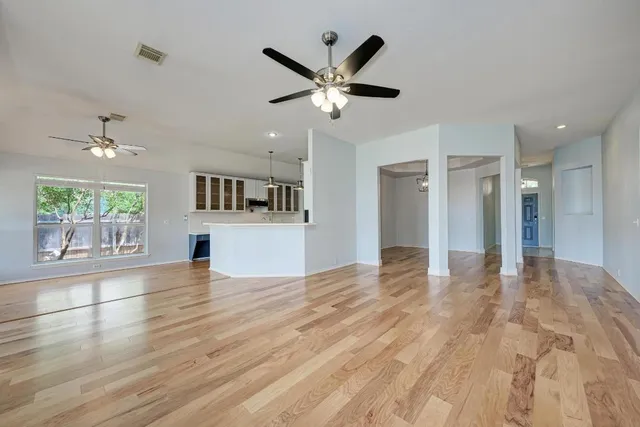 a view of empty room with wooden floor and fan