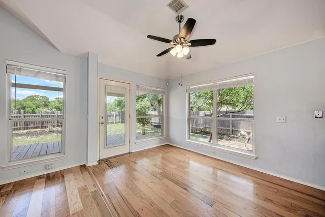 a view of a livingroom with a fireplace a ceiling fan and wooden floor