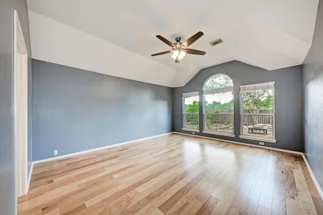 a view of a big room with wooden floor and windows