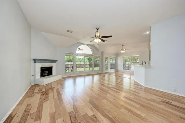a view of an empty room with a window and wooden floor