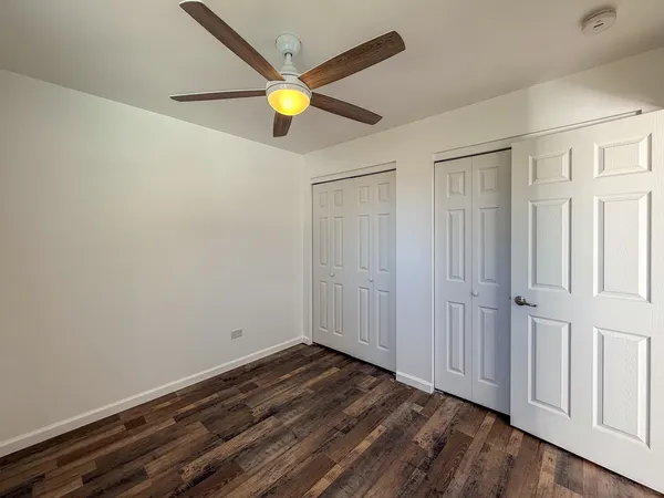 a view of a hallway with wooden floor and a bathroom