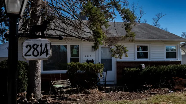 a front view of a house with plants and a tree