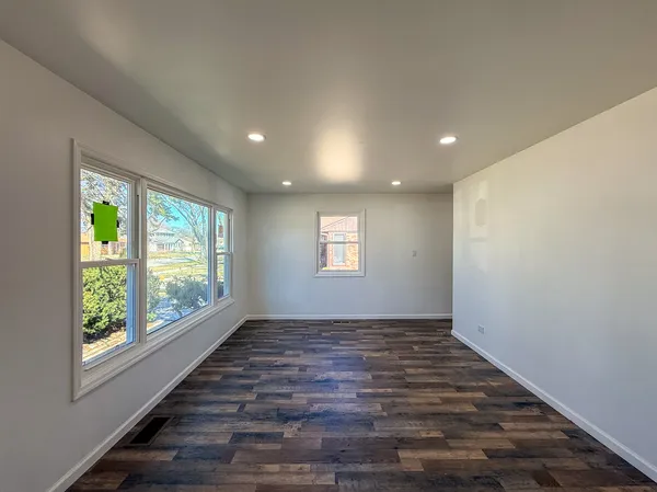 a view of an empty room with window and wooden floor