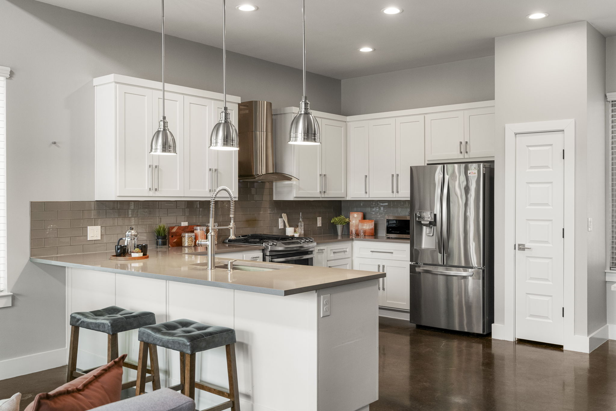 5204 Samuel Huston Avenue, Unit A Austin, TX 78721 - Photo 14 of 38 Contemporary kitchen featuring an island with integrated sink, stainless steel appliances, white shaker cabinetry, pendant lighting, and recessed ceiling lights
