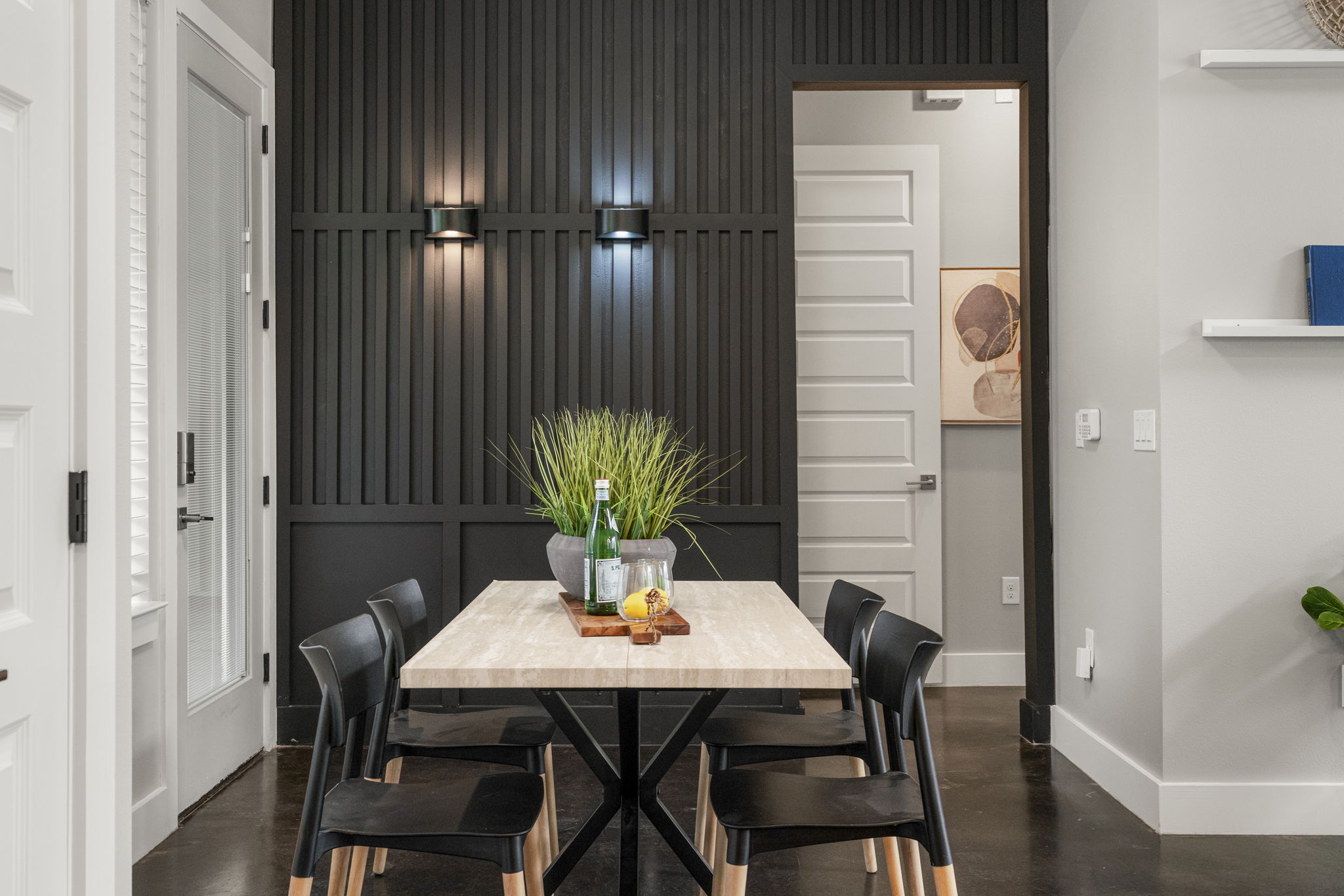 5204 Samuel Huston Avenue, Unit A Austin, TX 78721 - Photo 16 of 38 Dining area featuring a dark accent wall with vertical paneling and two wall-mounted sconces