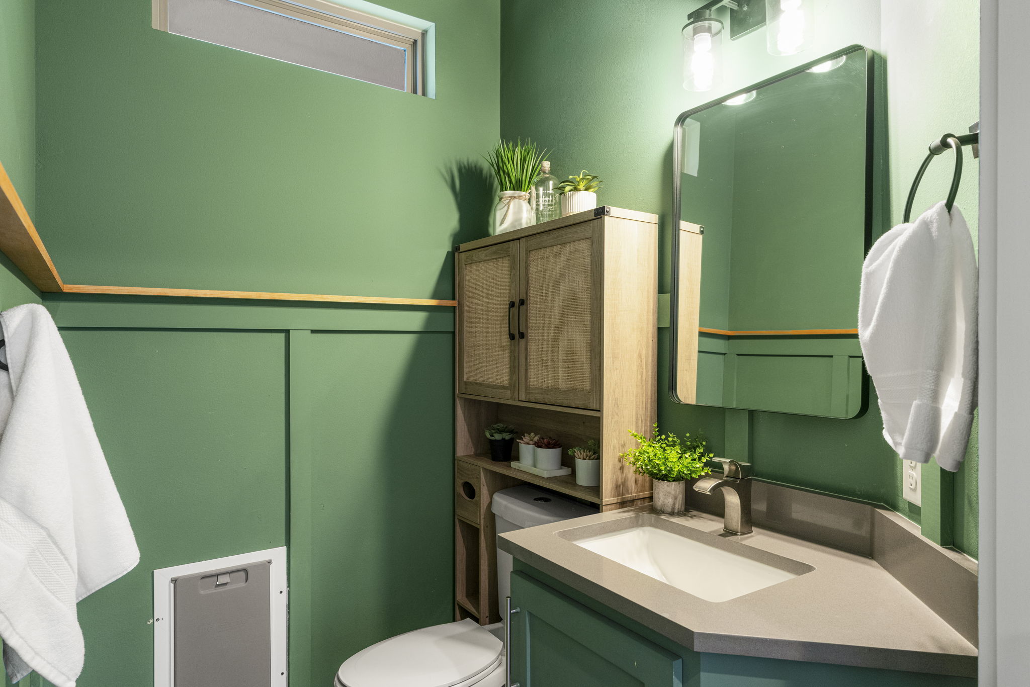 5204 Samuel Huston Avenue, Unit A Austin, TX 78721 - Photo 20 of 38 Bathroom featuring a green board and batten wall treatment with a wood-finish shelf, a vanity with an integrated sink and gray countertop, a wall-mounted mirror, and a wood-finish storage cabinet