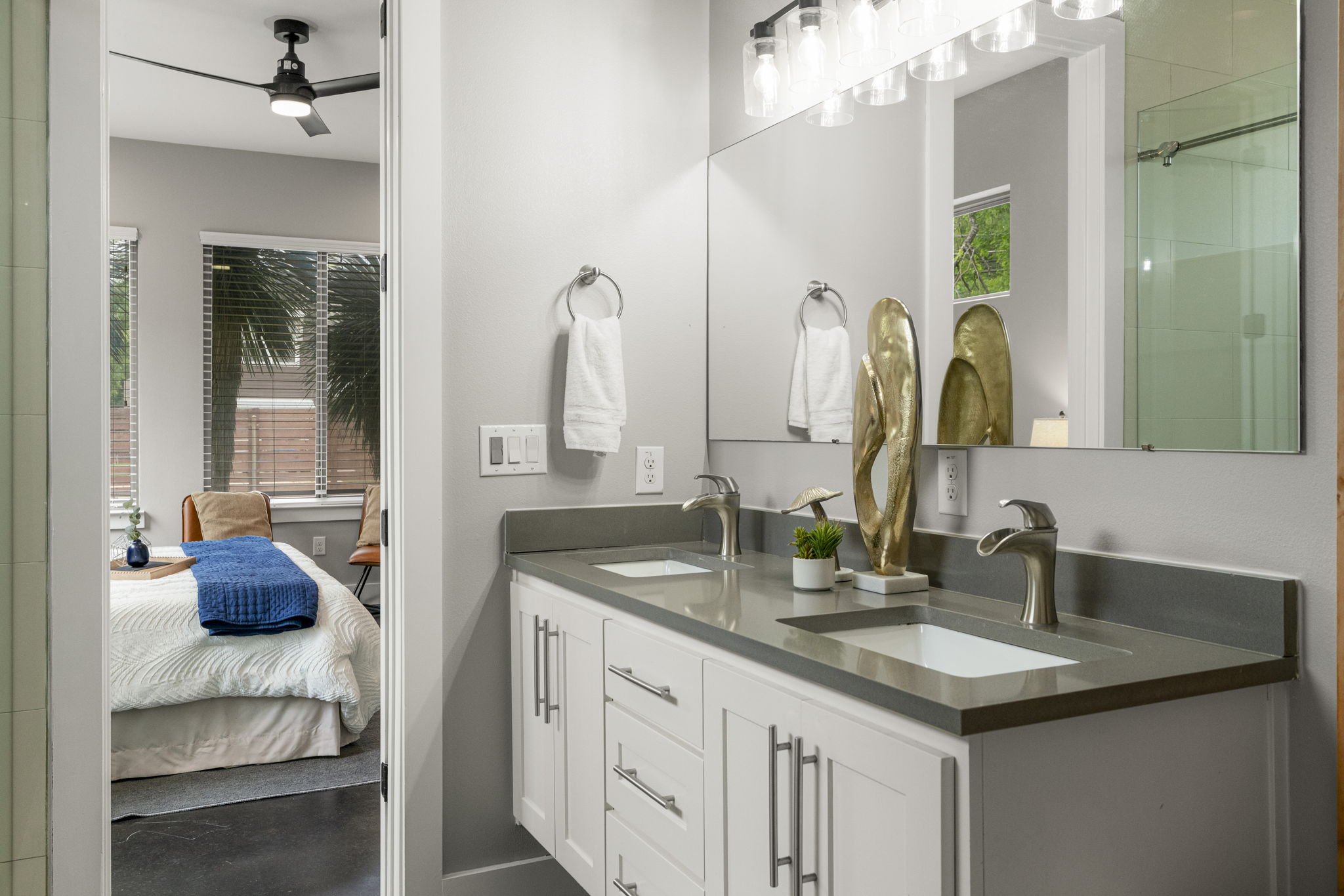 5204 Samuel Huston Avenue, Unit A Austin, TX 78721 - Photo 23 of 38 Dual vanity featuring white shaker cabinetry, brushed nickel hardware, and a stone-finish countertop with integrated sinks