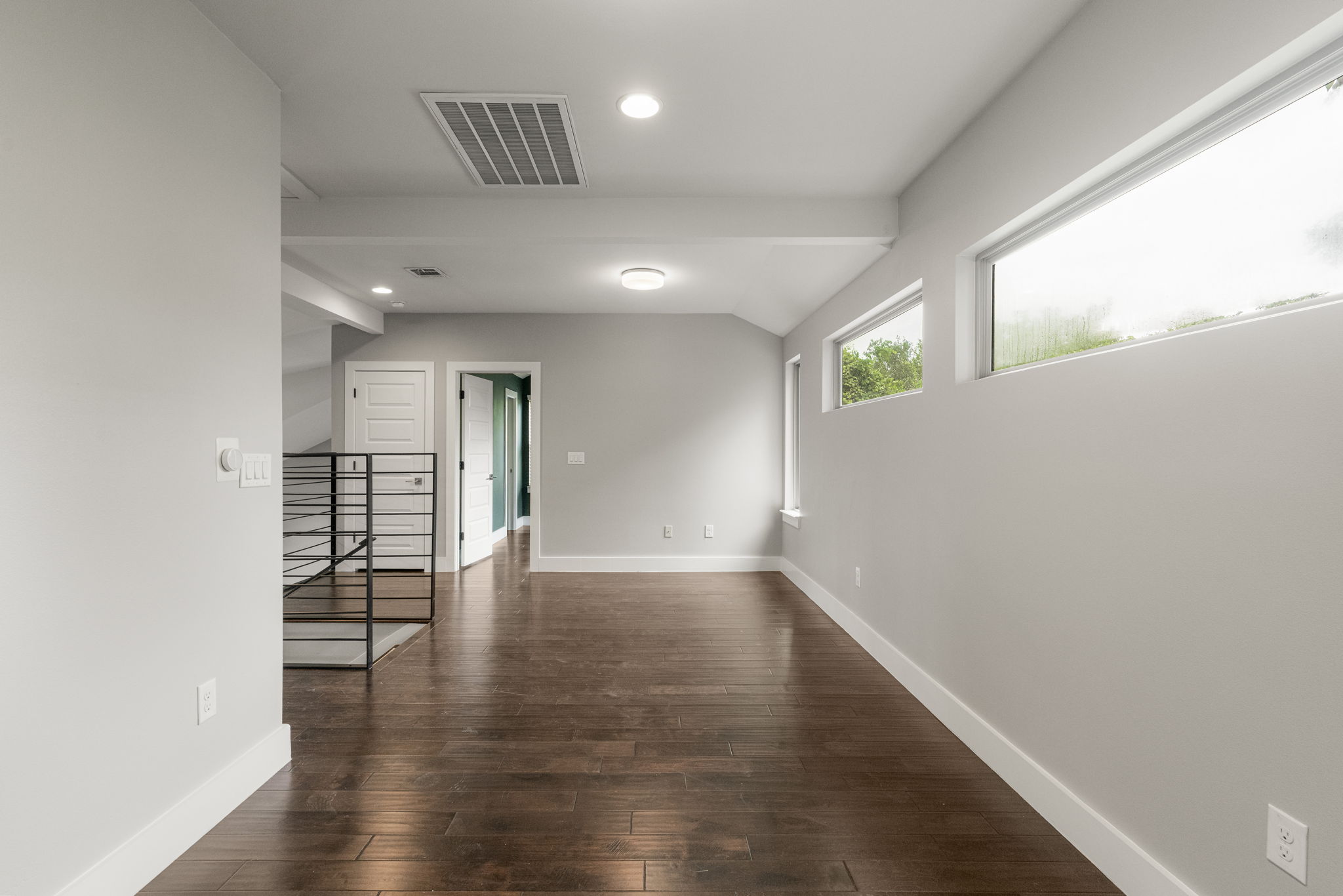 5204 Samuel Huston Avenue, Unit A Austin, TX 78721 - Photo 26 of 38 Spacious room featuring wood-finish flooring, light grey walls, white trim, and multiple horizontal windows