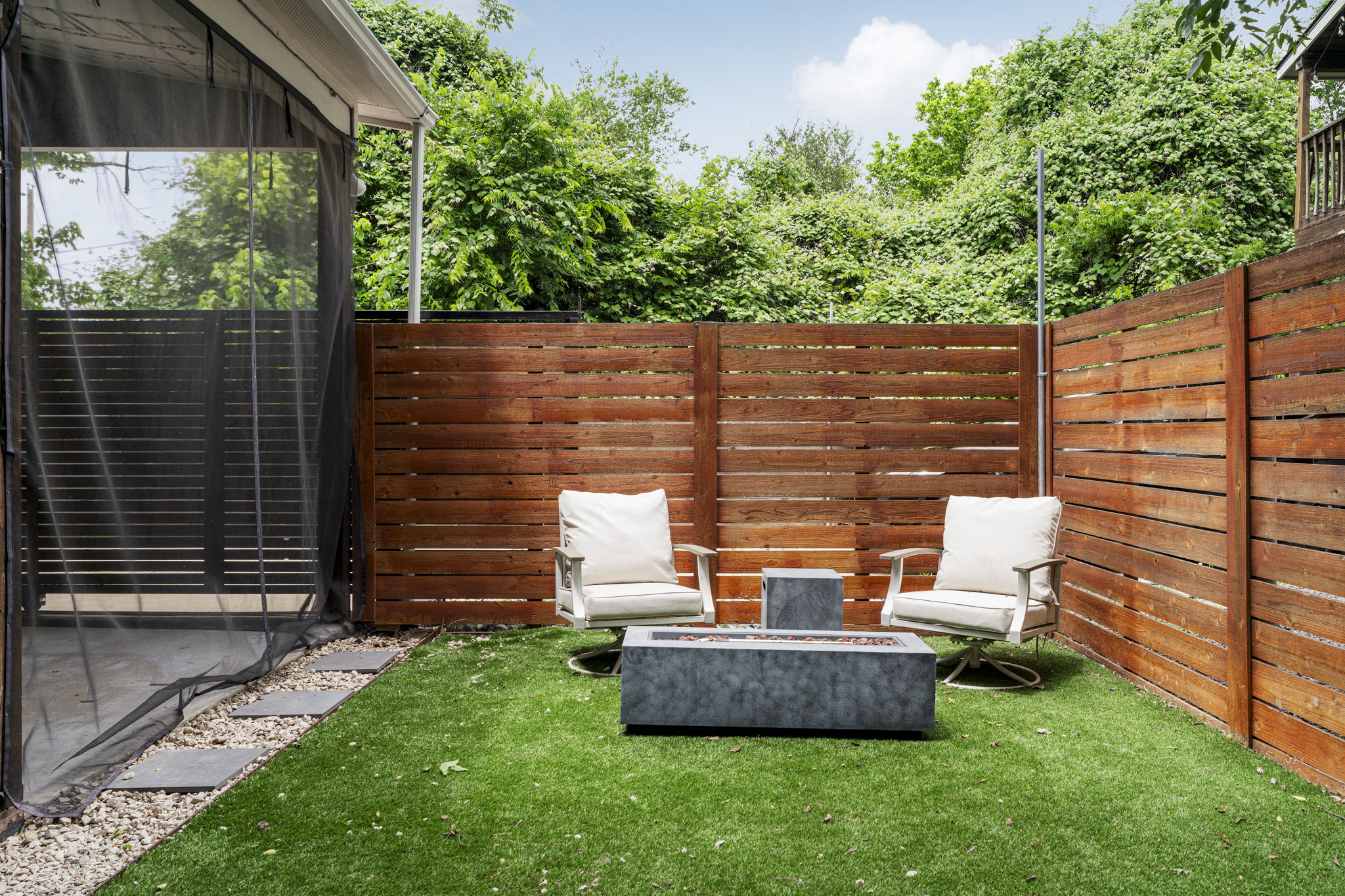 5204 Samuel Huston Avenue, Unit A Austin, TX 78721 - Photo 32 of 38 Enclosed patio area featuring artificial turf, a decorative fire pit, and a horizontal slat wood fence