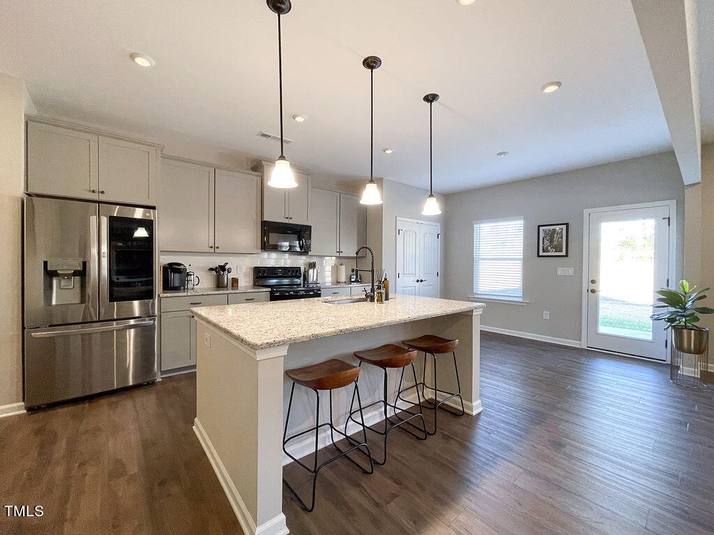 3604 Cross Timber Lane Raleigh, NC 27603 - Photo 3 of 15 a kitchen with stainless steel appliances granite countertop a refrigerator a stove a sink dishwasher a refrigerator white cabinets and wooden floor
