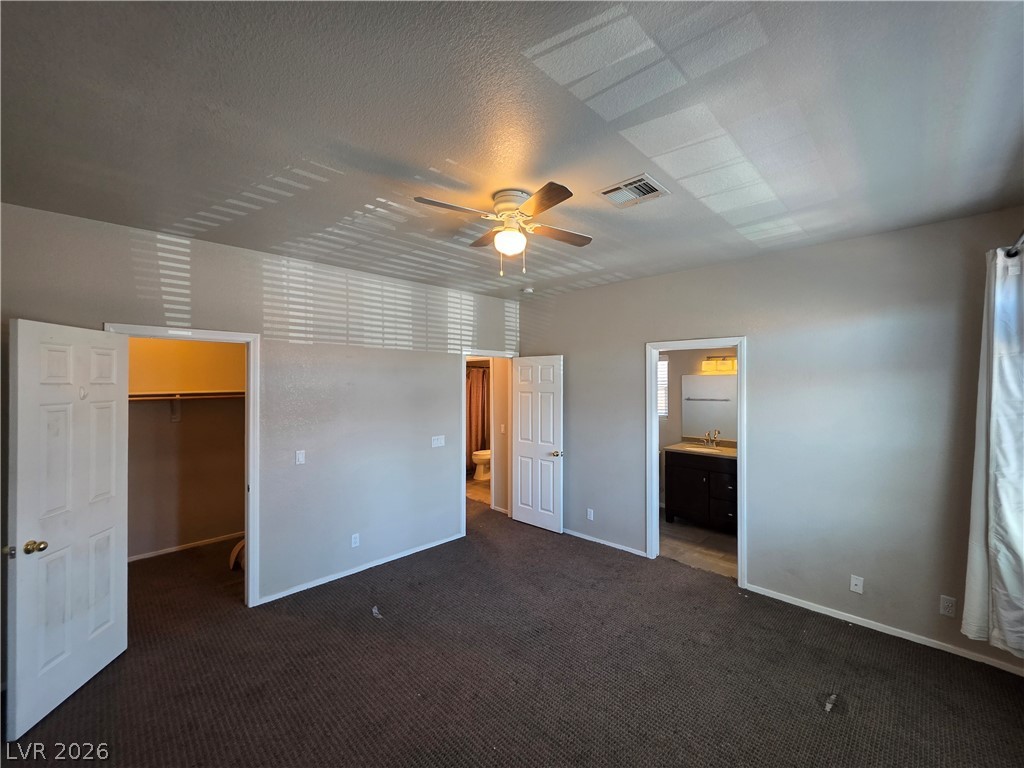 2275 Ramsgate Drive Henderson, NV 89074 - Photo 51 of 84 A spacious primary bedroom featuring plush carpeting, a ceiling fan, and convenient ensuite bathroom access.
