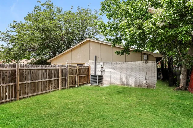 a view of a small house with a big yard and large trees