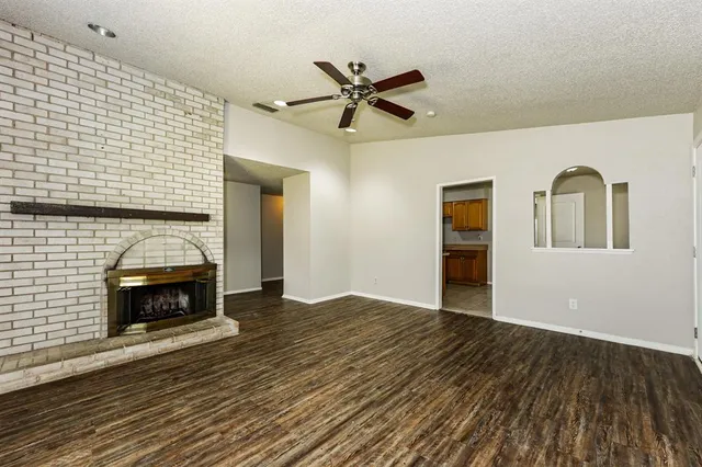 a view of an empty room with wooden floor fireplace and a window