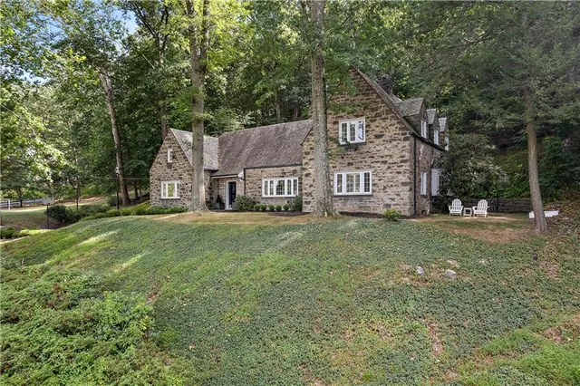 a view of a big house with a big yard and large trees
