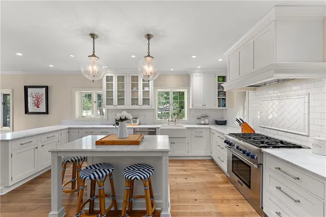 a kitchen with stainless steel appliances granite countertop a stove top oven a sink dishwasher and white cabinets with wooden floor