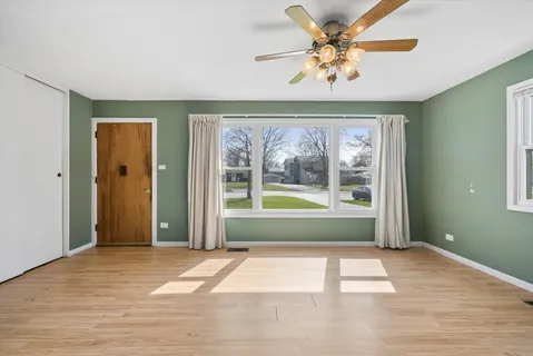 a view of a livingroom with a large window a ceiling fan and front door