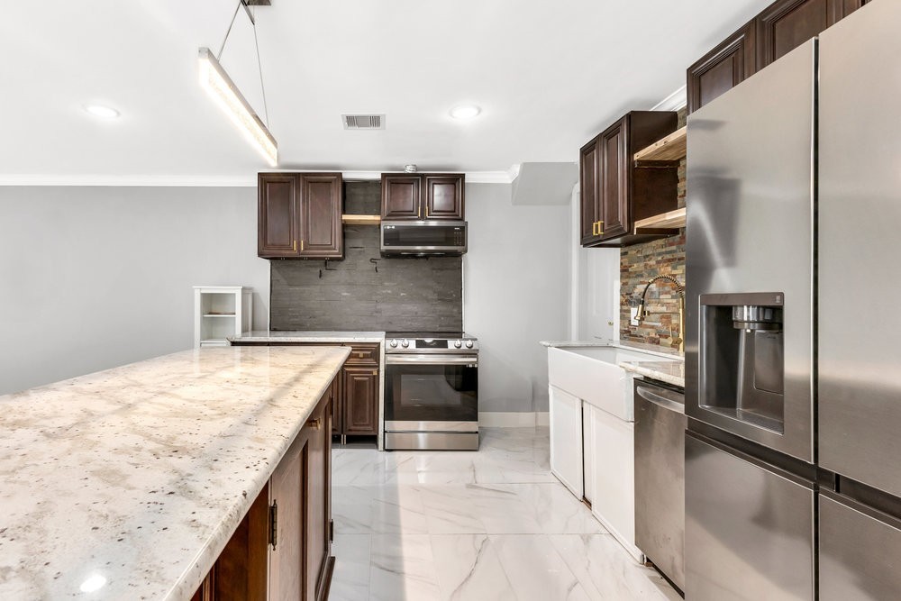 6325 Riverview Way, Unit ABCD Houston, TX 77057 - Photo 18 of 33 a kitchen with stainless steel appliances granite countertop a refrigerator a stove and a sink with wooden floor