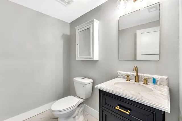 a bathroom with a granite countertop toilet sink and mirror