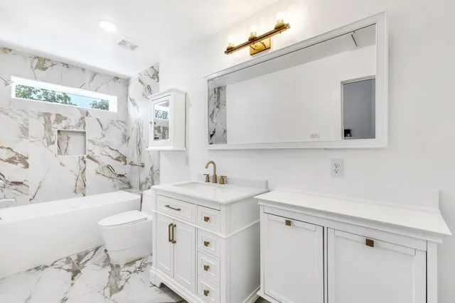 a bathroom with a sink a toilet a mirror and shower