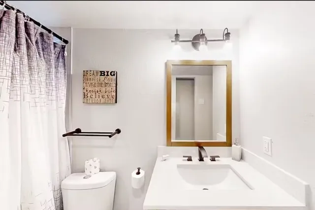 a bathroom with a sink mirror and a toilet