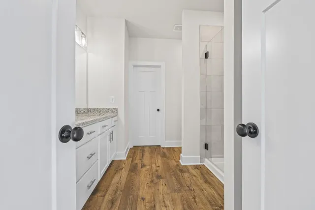 a bathroom with a granite countertop sink a large mirror and shower
