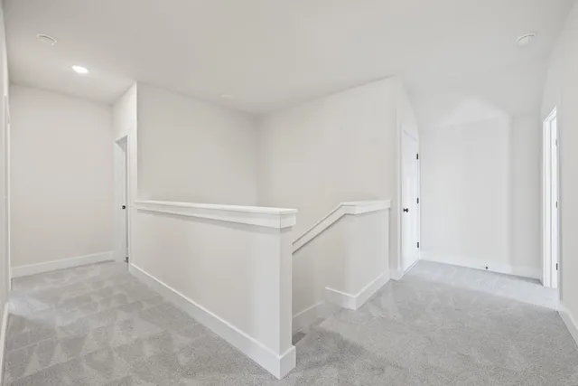 a view of a hallway to an empty room with wooden floor