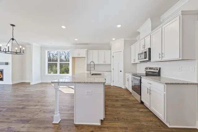 a large white kitchen with wooden floor and stainless steel appliances