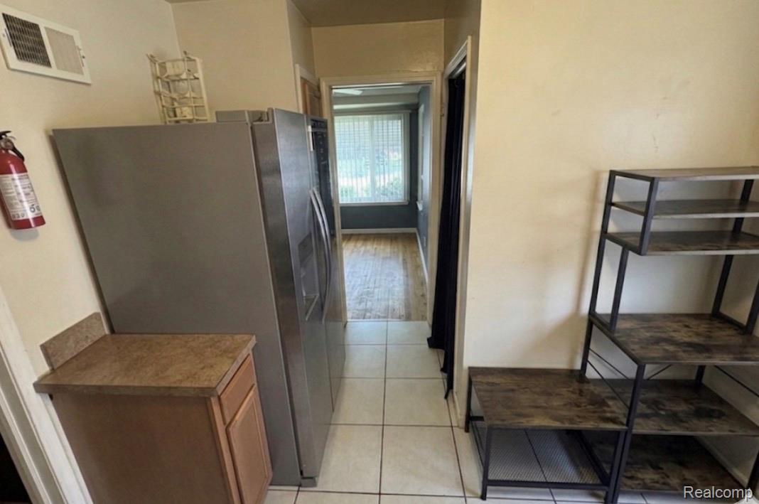 Kitchen featuring stainless steel fridge, light tile patterned floors, and wood finish cabinetry