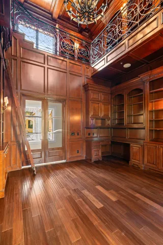 a view of an empty room with wooden floor and windows