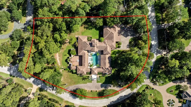an aerial view of residential house with outdoor space and trees all around