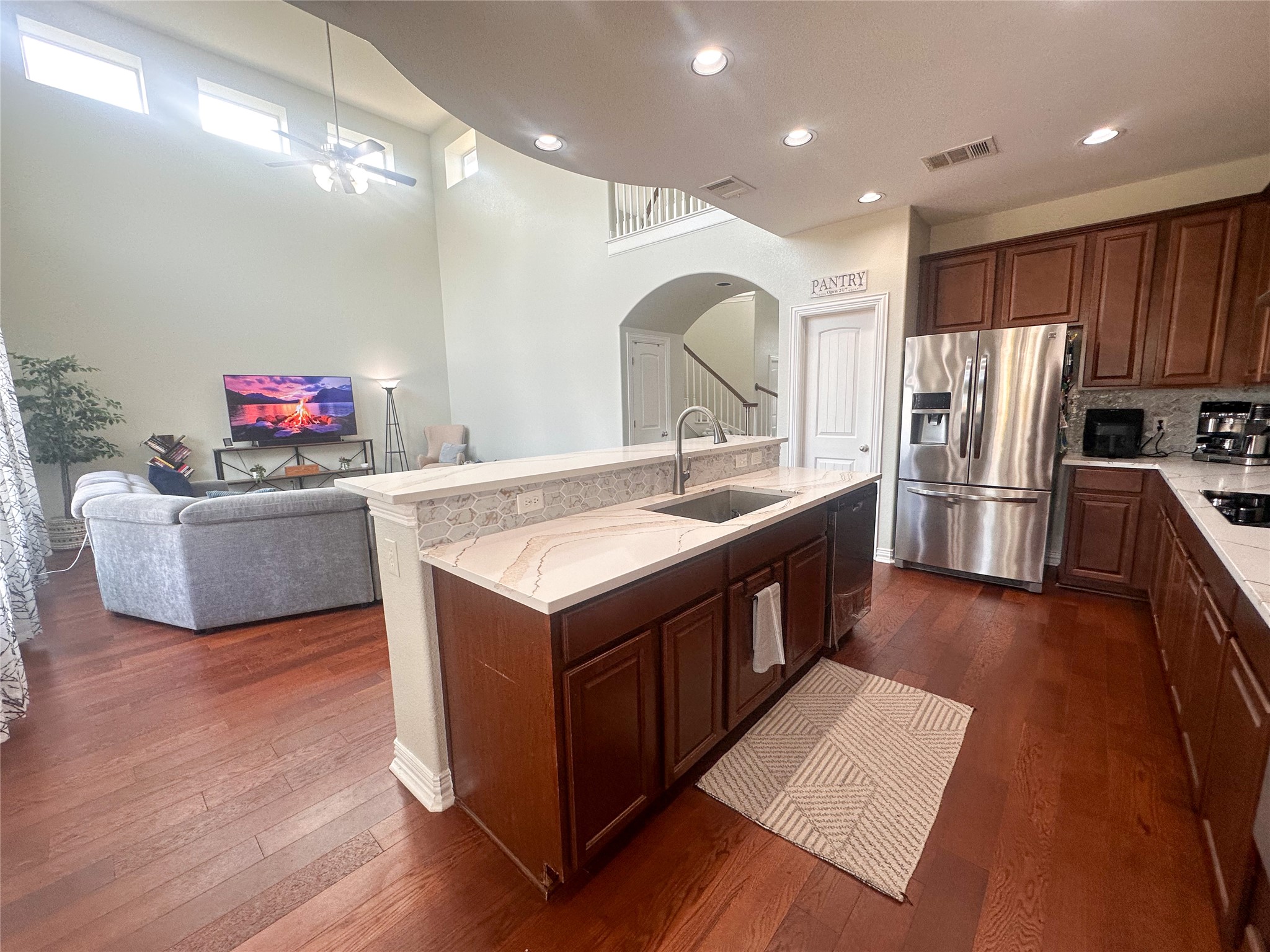 237 Cardinal Drive Paige, TX 78659 - Photo 6 of 37 Kitchen with dark wood finished floors, a kitchen island with sink, stainless steel appliances, arched walkways, and light stone counters