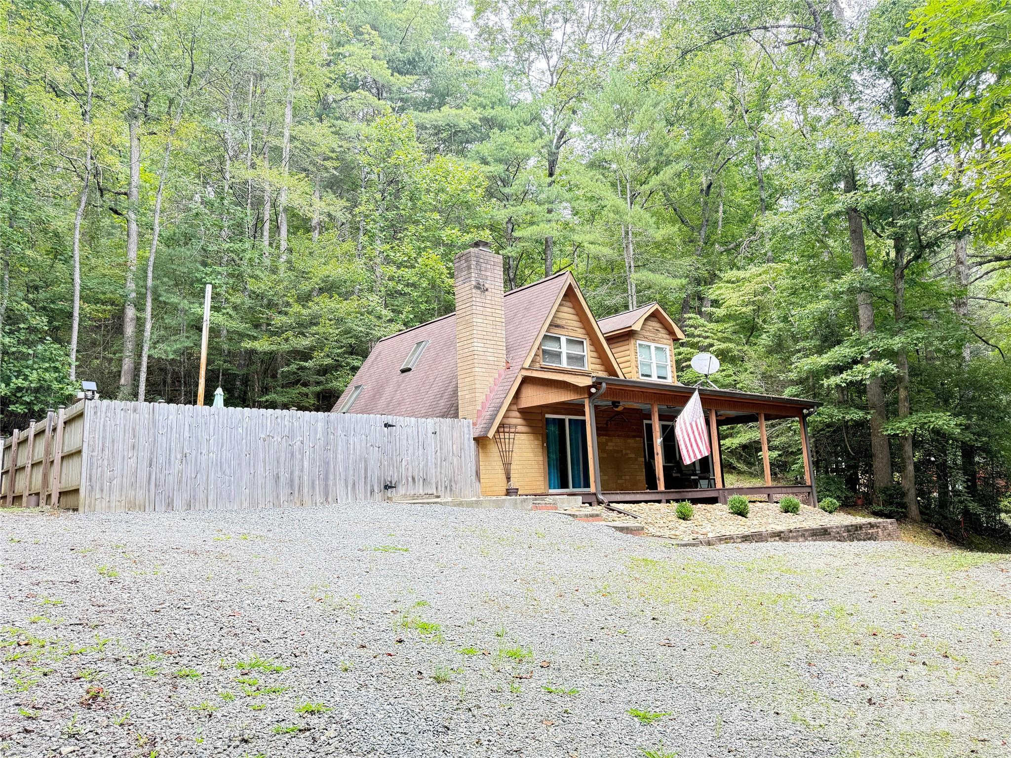 a view of a house with large trees and wooden fence