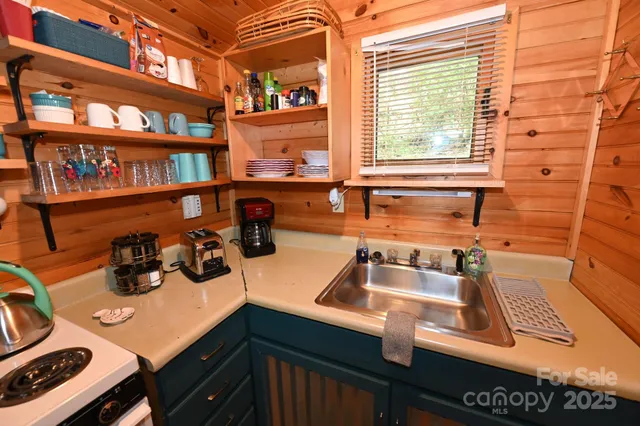 a living room with stainless steel appliances furniture a flat screen tv and kitchen view
