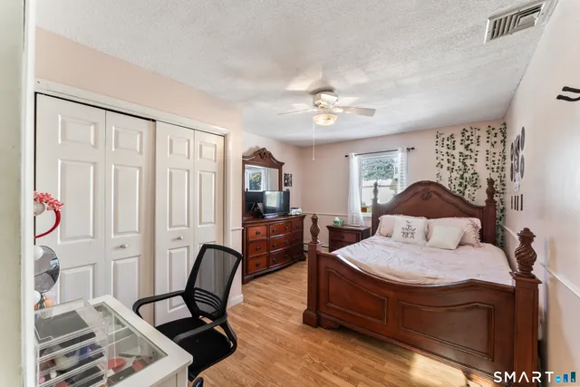 a bedroom with a bed and a bookshelf with wooden floor