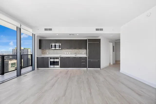 a view of kitchen with stainless steel appliances wooden floor and more cabinets