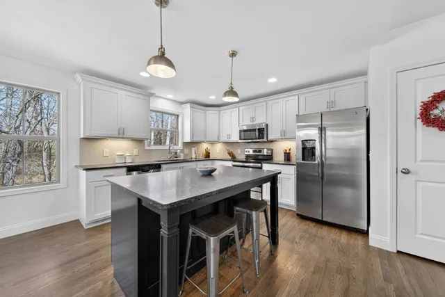 a kitchen with stainless steel appliances granite countertop a sink a stove top oven a refrigerator and cabinets